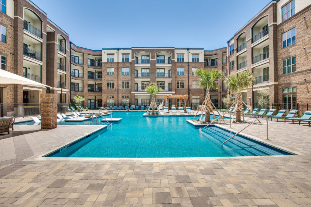 Large resort-style swimming pool with palm trees in central courtyard