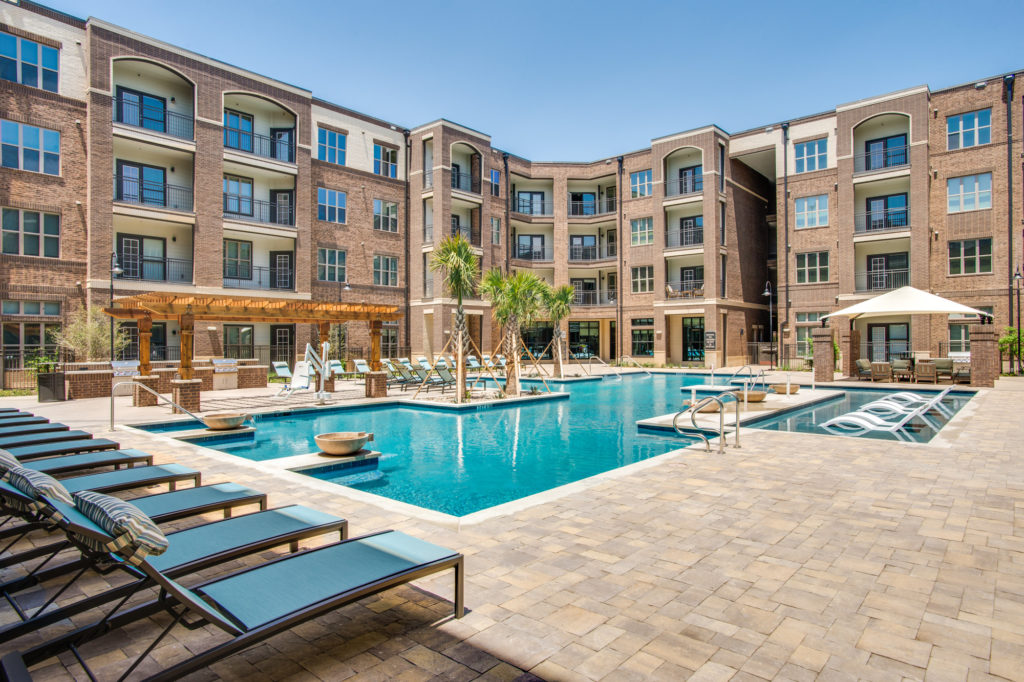 Large resort-style pool with loungers, covered gazebo seating, and pergola